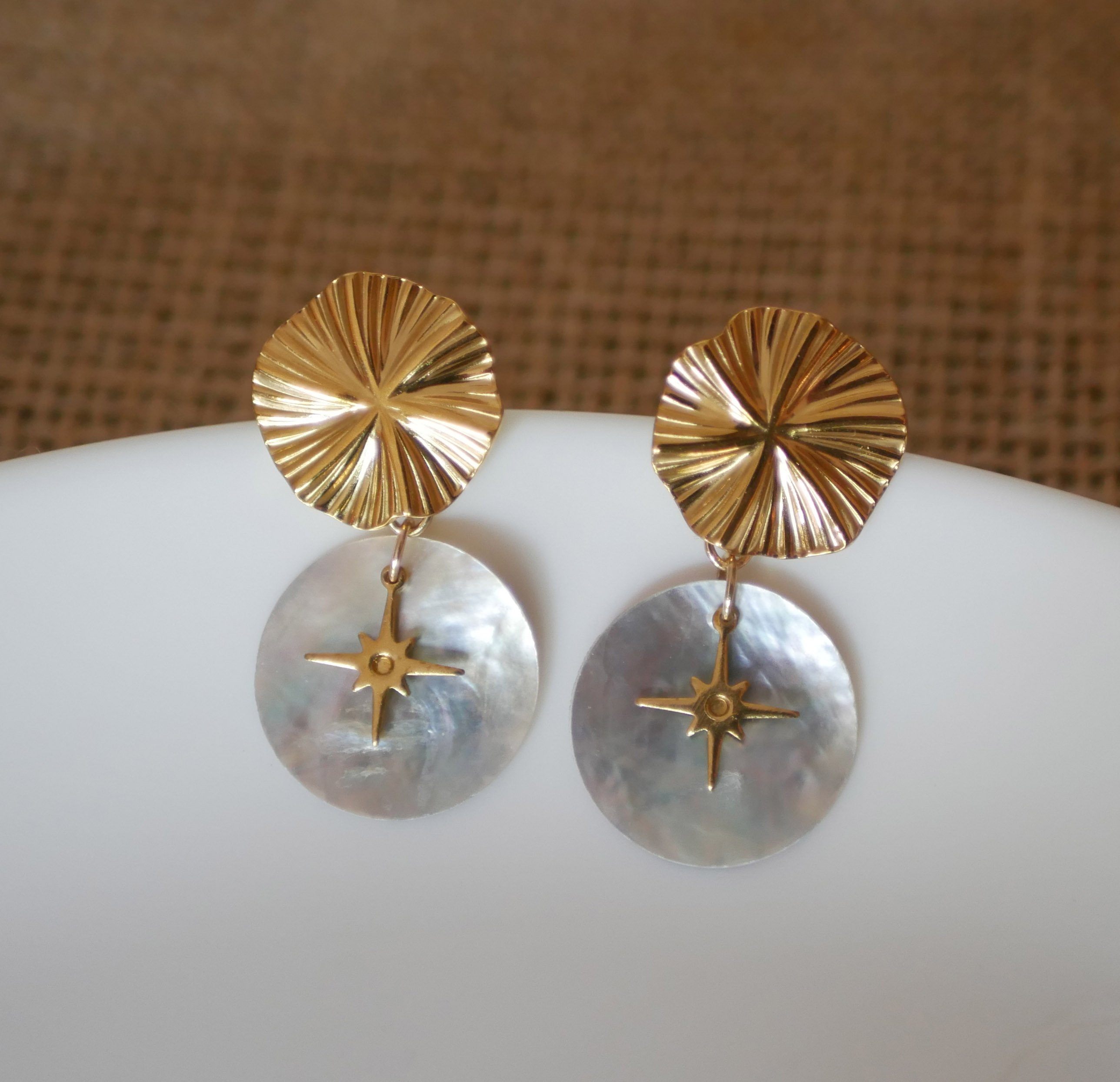 Oorbellen uit de collectie "Les nacrées", gouden schijf met geplooid effect en windroos