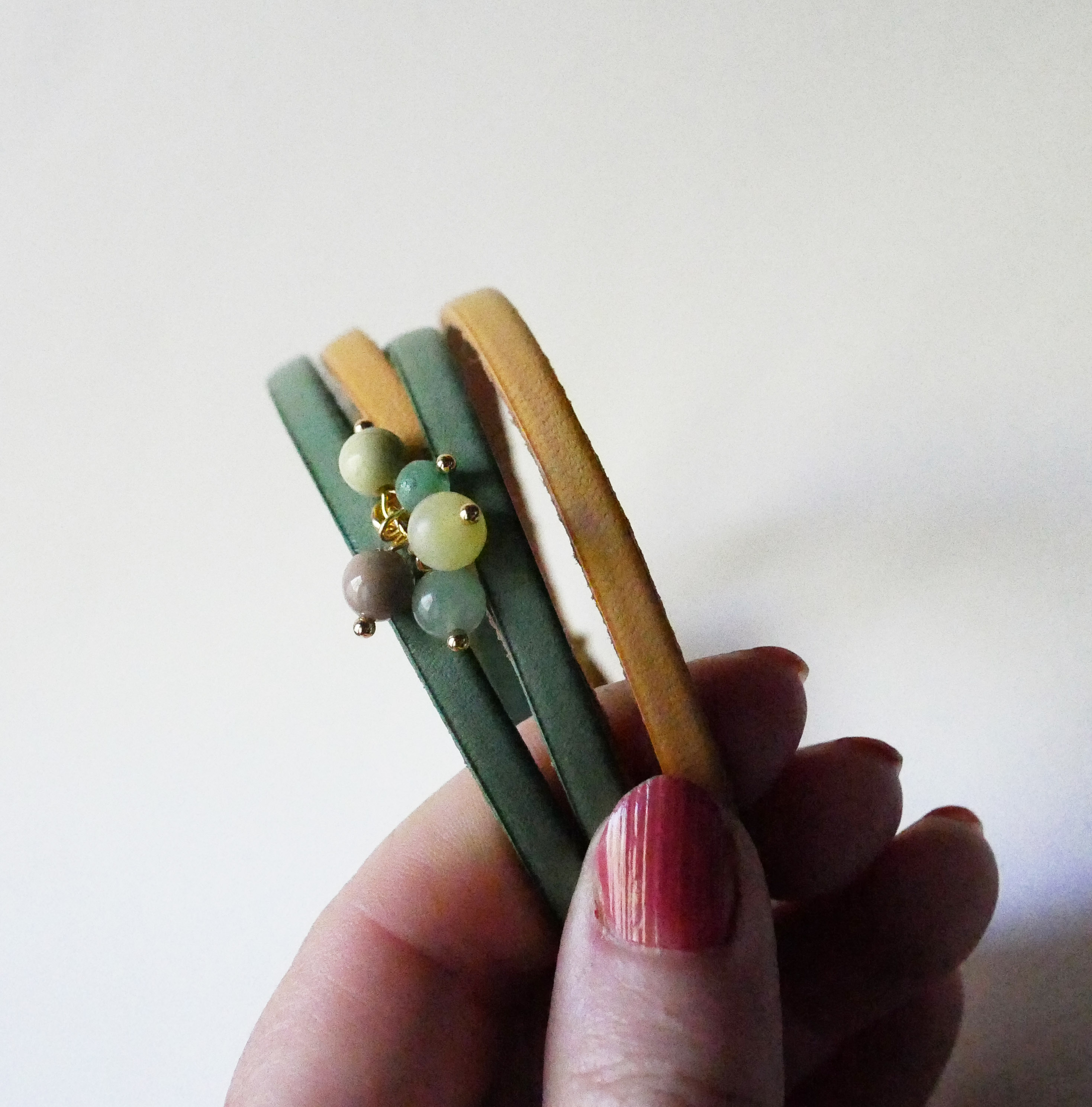 Dubbele leren armband versierd met zachtgroene parels en gouden sluiting
