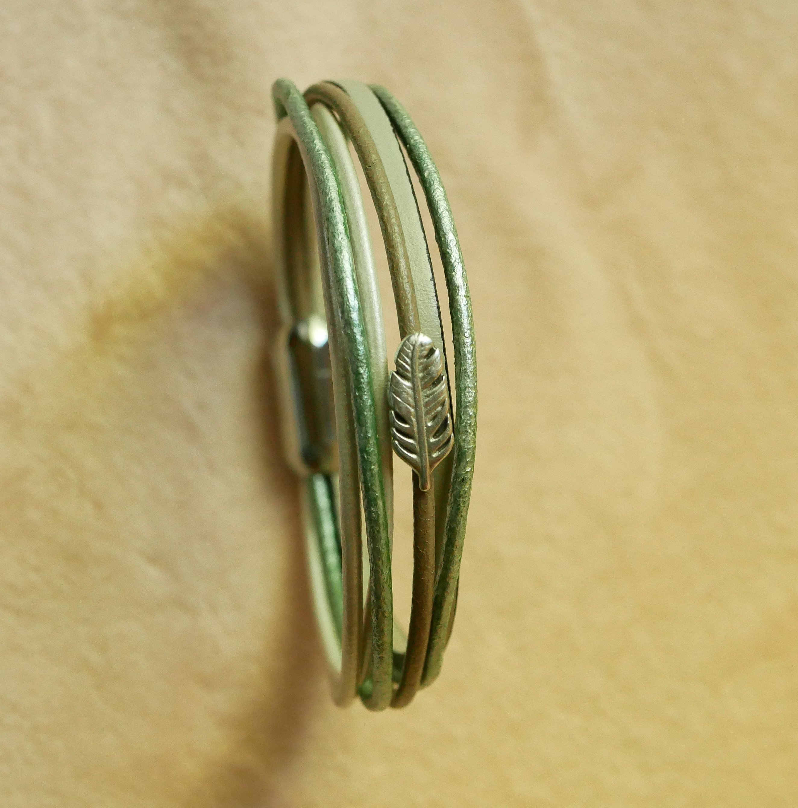 Multileren armband in beige, lichtgroen en parelmoer, versierd met een veertje