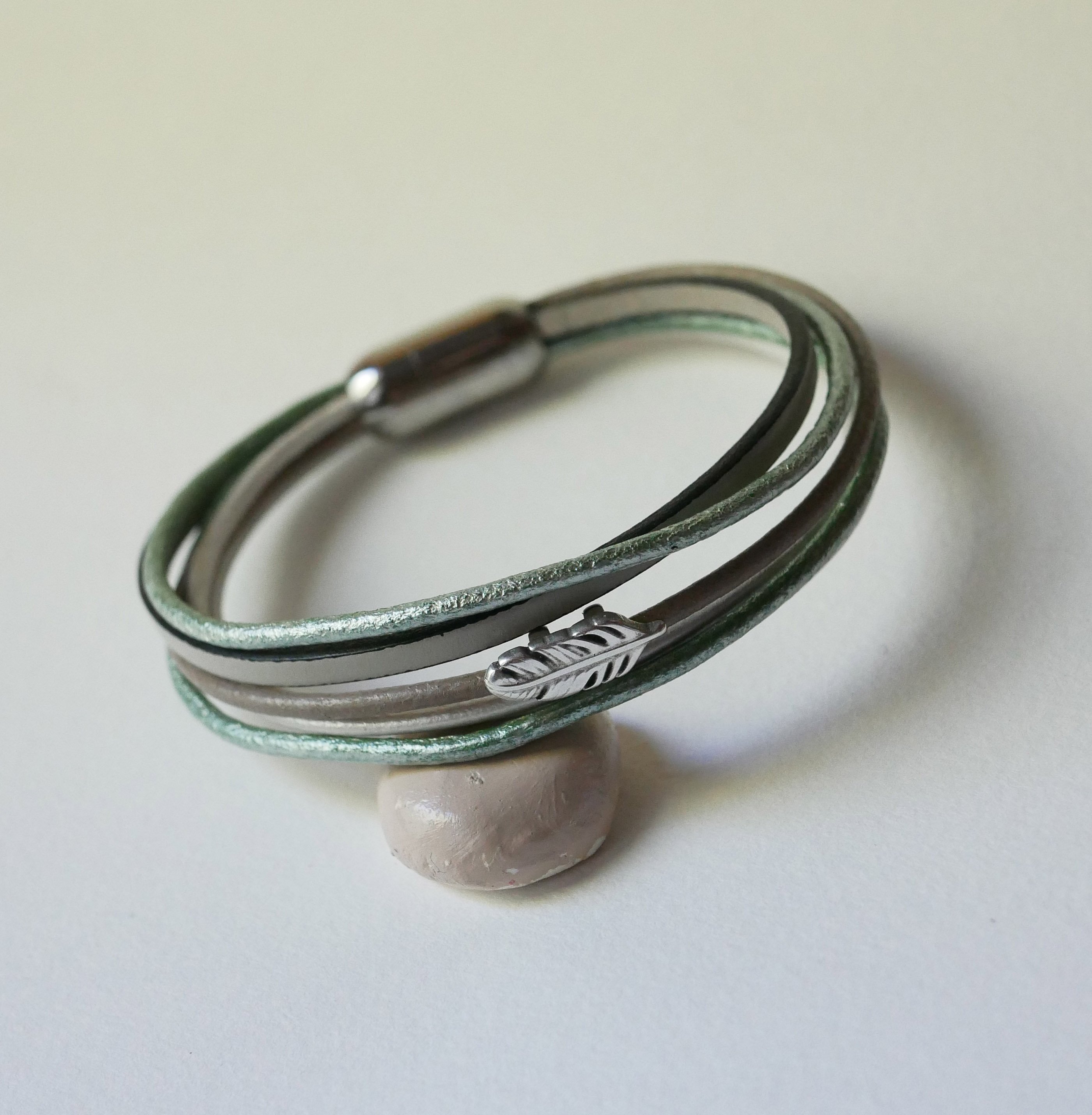 Multileren armband in beige, lichtgroen en parelmoer, versierd met een veertje