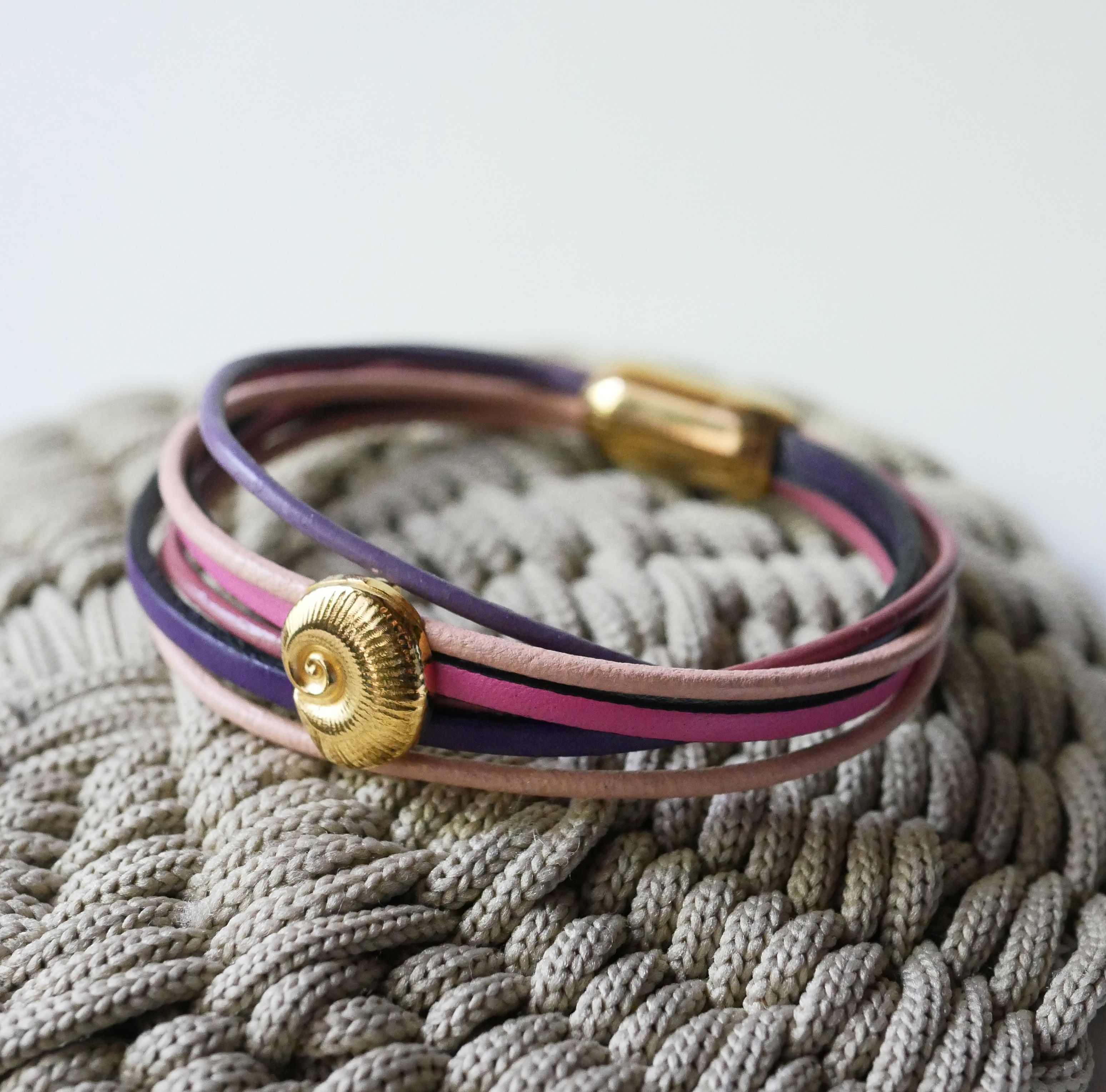 Multilink-armband van perzik- en mauveleer met goudkleurige schelpversiering