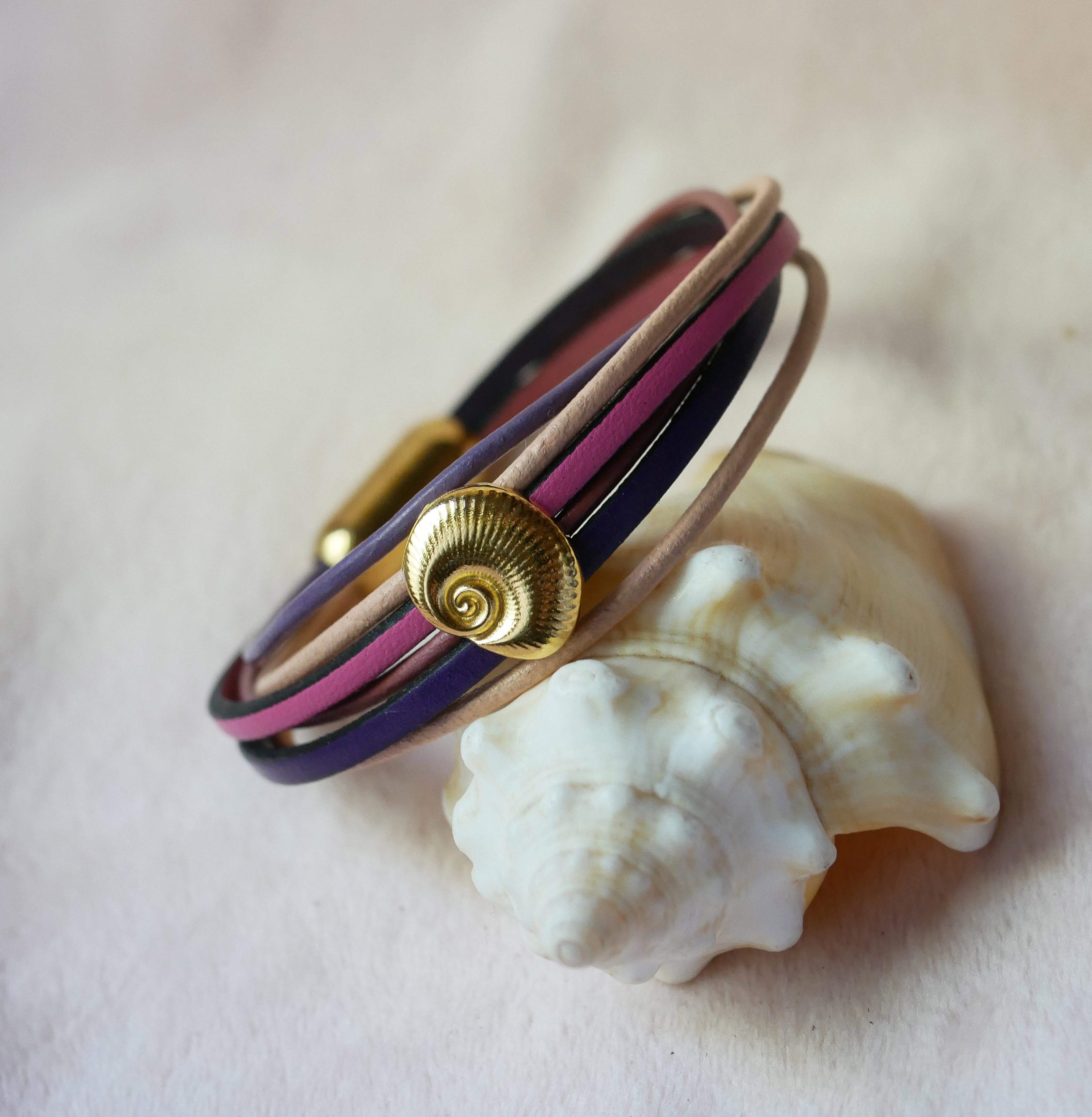 Multilink-armband van perzik- en mauveleer met goudkleurige schelpversiering