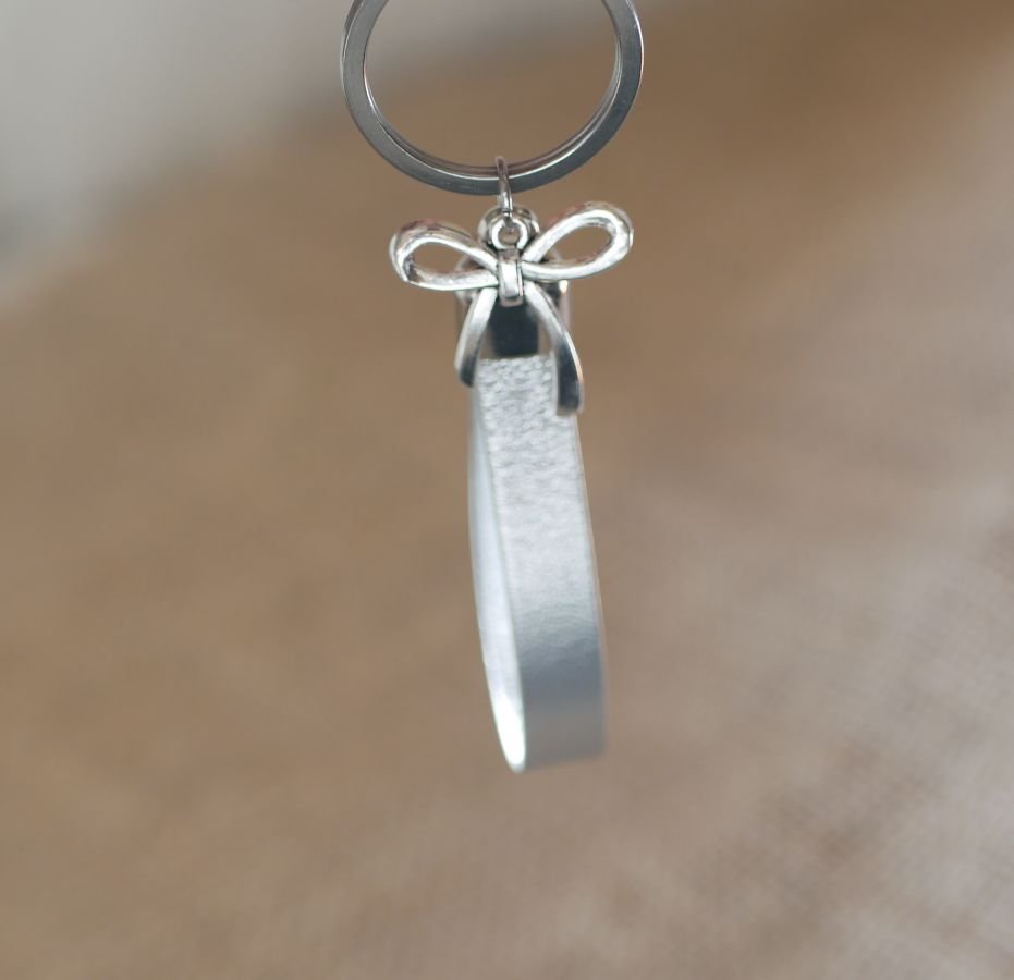 Leren sleutelhanger te personaliseren door gravure versierd met een strikje