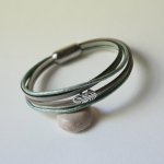 Multileren armband in beige, lichtgroen en parelmoer, versierd met een veertje